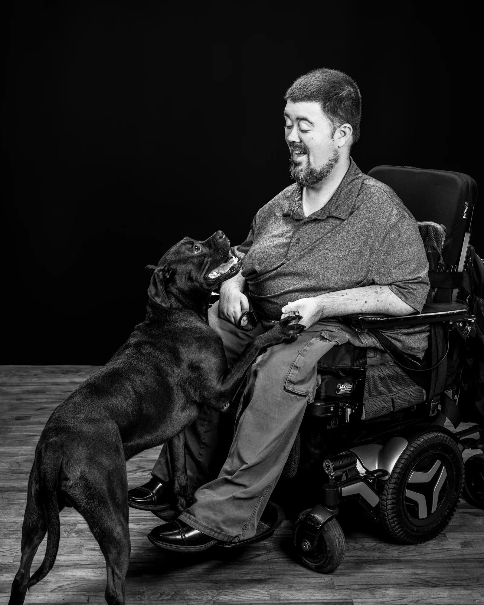 Greg Wessels laughing as his dog Atlas rests a paw in his hand